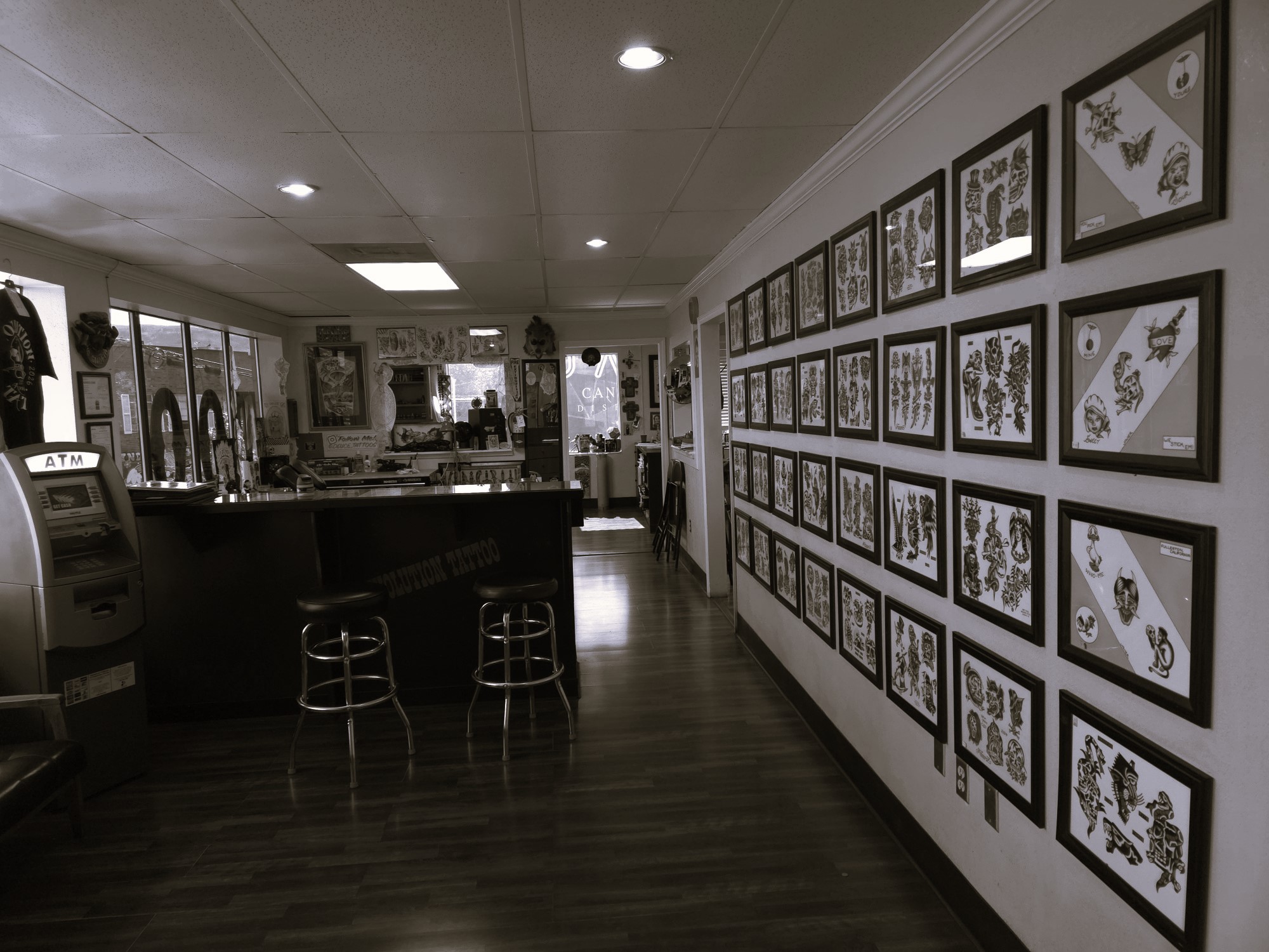 Interior of Evolution Tattoo studio in Reno, NV — reception counter, barstools, and a wall of framed tattoo flash art